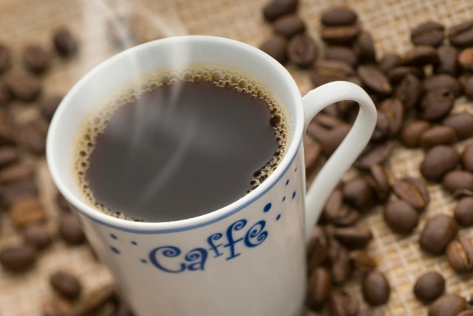 a cup of coffee sitting on top of a pile of coffee beans